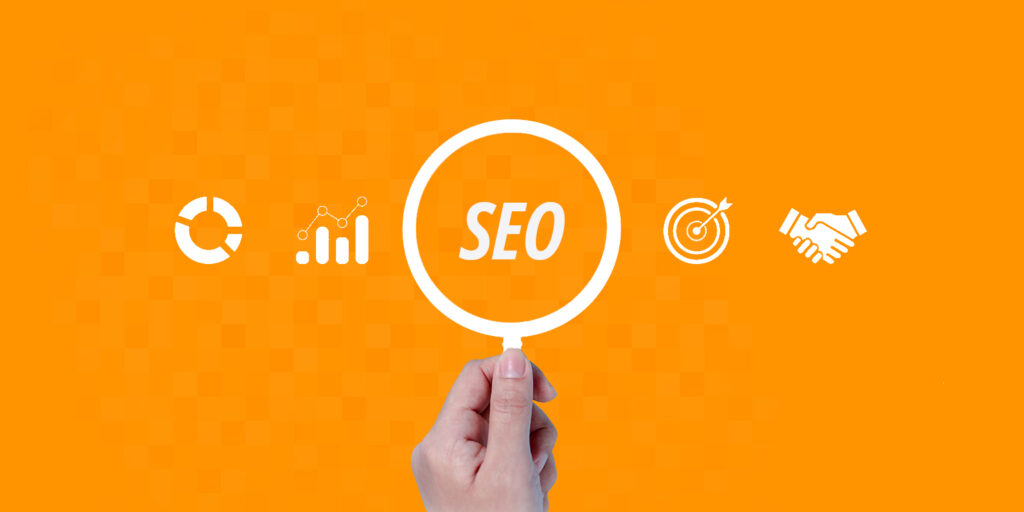 Uma imagem ilustrativa com uma mão segurando uma lupa que exibe a palavra 'SEO' em letras brancas no centro. A lupa está alinhada horizontalmente com quatro ícones brancos planos: um gráfico de pizza e um gráfico de barras com linha de tendência à esquerda, e um alvo com flecha e um aperto de mão à direita. O fundo é de cor laranja vibrante com um padrão sutil de mosaico de pixels.